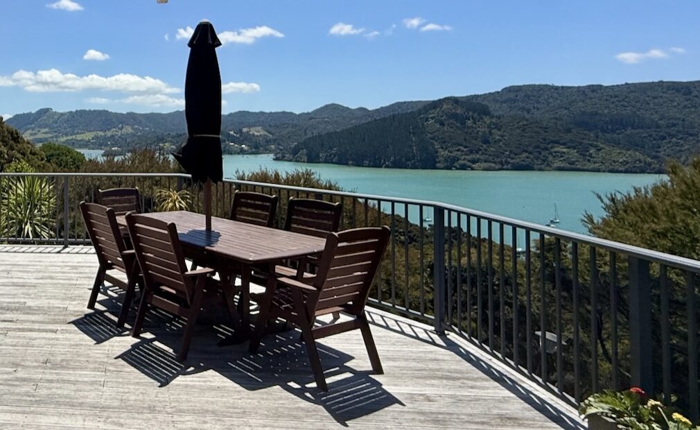 Large picnic table with umbrella on pool deck of King's View Lodge with scenic overlook of Whanagaroa Harbour